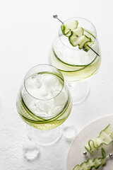 Cucumber infused detox water in glasses with ice. Homemade flavored lemonade on white gray background close up text space