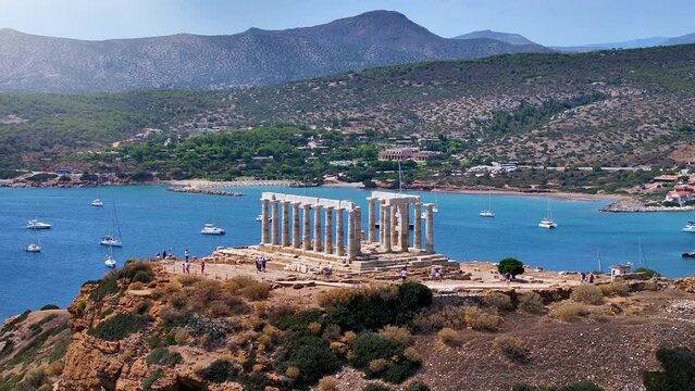 The ancient Temple of Poseidon at the bay of Cape Sounion at the edge of Attica, Greece, during summer time