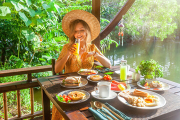 Woman enjoying healthy tropical fruit breakfast at beautiful resort. Concept of summer vacation and...