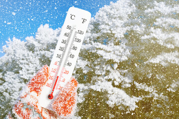 Winter holidays with snow. White celsius scale thermometer in hand. Ambient temperature minus 13...