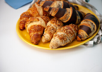 Chocolate croissants or croissant with nut crumbs on a plate. Delicious breakfast on the table. Tasty sweet baking dessert for coffee. Food background. Fresh buttery croissants rolls