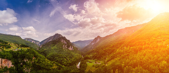 Panorama of high mountains of Tara river canyon at sunset with cloudy sky.