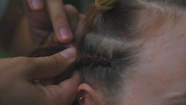 Process of weaving making boxer braids cornrows by a hair braider.