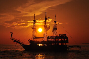 Historical ship and observing pirate at sunset.
