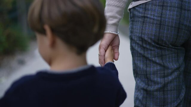 Parent holds the hand of a little child. Trust family concept. Mother holding hands with son walking together outdoors in motion
