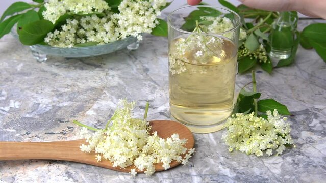 Homemade elderflower drink with sugar and lemon in a glass, light background