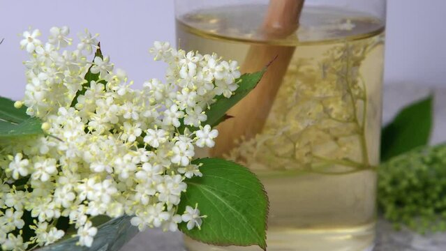 Homemade elderflower drink with sugar and lemon in a glass, light background