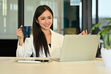 Friendly, smart young businesswoman talking by conference online virtual chat via laptop computer at office