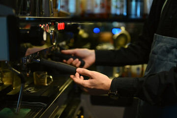 Professional barista using coffee machine, making espresso for client in a trendy cafe