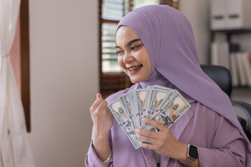 happy young Cheerful business asian islamic woman in hijab  holding a lot of money that her has...