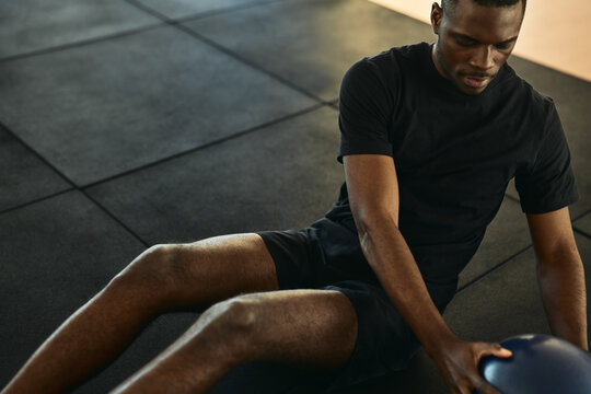 Black sportsman doing exercise with medicine ball