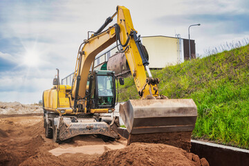A powerful wheeled excavator prepares the site for the construction of the railway. Excavator with a wide bucket leveling the surface of the railway track. Excavation.