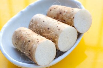 Fresh nagaimo on yellow background.