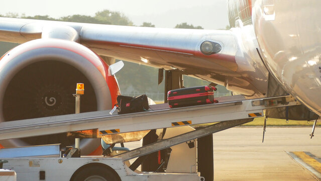process of carrying luggage bag on a conveyor belt to airplane before departure while traveling at the airport