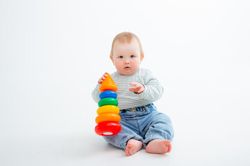 charming baby in a T-shirt and jeans is playing with toy pyramid, a postcard, a banner, a place for text. High quality photo