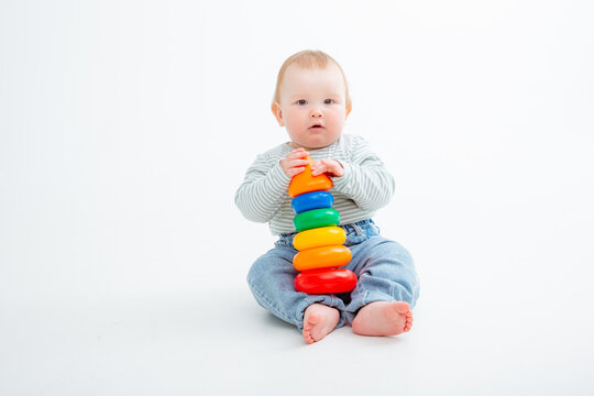 charming baby in a T-shirt and jeans is playing with toy pyramid, a postcard, a banner, a place for text. High quality photo
