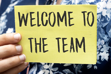 woman hand holding a yellow cardboard with WELCOME TO TEAM text concept