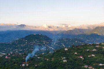 Mountain settlement in Georgia. Mountain village near Batumi. Caucasus mountains with clouds. Houses in the mountains. Evening mountain landscape.