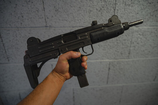 Submachine gun in a man's hand, close-up photo.