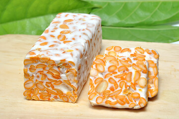 Slice of tempeh on wooden table green leaf background