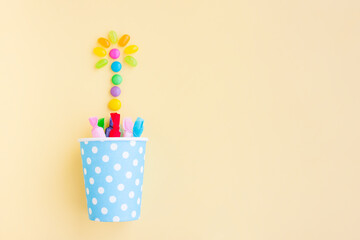 Different kinds of colorful candy out of a blue paper cup with white dot on yellow background, Various candies