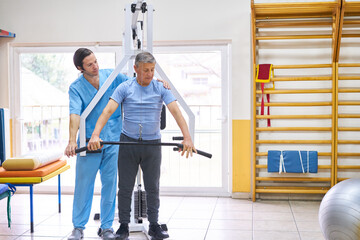Fototapeta na wymiar Physiotherapist training elderly man at rehab center