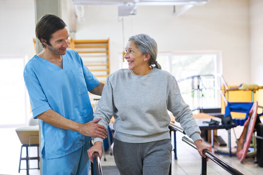 Male therapist assisting senior woman in movement therapy