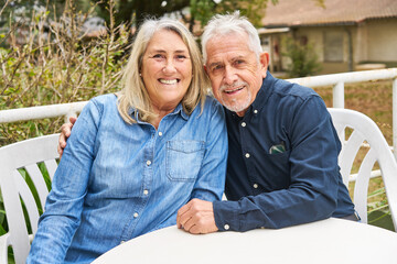 Cheerful senior couple sitting at table in garden