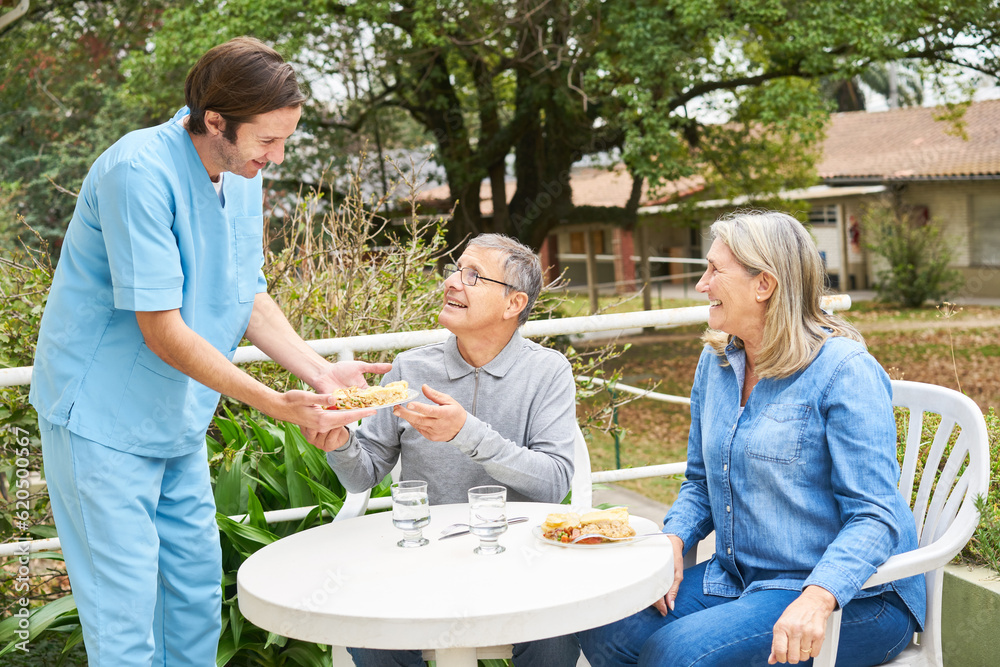 Wall mural caregiver with senior people having meal in garden of nursing home