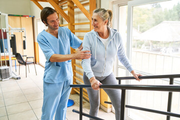 Physiotherapist assisting elderly woman in movement therapy at rehab center