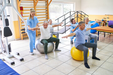 Group of elderly people exercising on fitness ball at rehab center