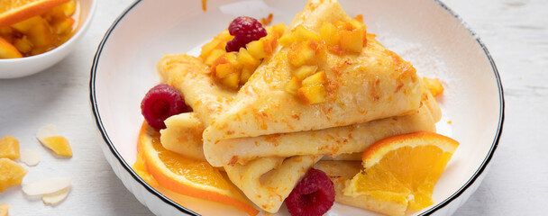 Crepe suzette with orange sauce and raspberry for a delicious breakfast.