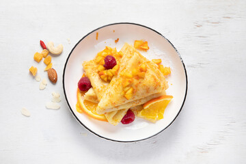 Crepe suzette with orange sauce and raspberry for a delicious breakfast.