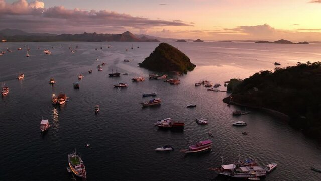 Aerial view of sunset in Labuan Bajo harbour with luxury cruise boats, vacation in Indonesia in Komodo national park, exotic tropical port of Labuan Bajo