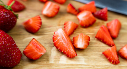 Ripe strawberries in slices on a wooden board. Cooking delicious dessert with fresh strawberries. Close-up. Selective focus.