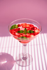 Strawberry refreshing cocktail with fresh mint on pink background with shadows. Close-up. Selective focus.
