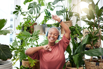 Music, dance and headphones with a black woman in her home by plants while streaming an audio...