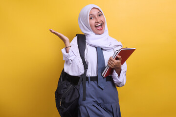 Cheerful female Indonesian high school student in white and grey uniform holding books