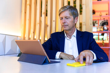 Cafeteria Productivity: Middle-aged Businessman Maximizing Efficiency with Tablet