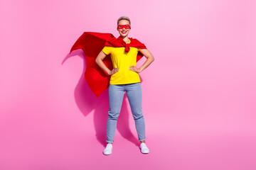 Full size portrait of positive strong super girl put hands waist wear red cape costume empty space isolated on pink color background