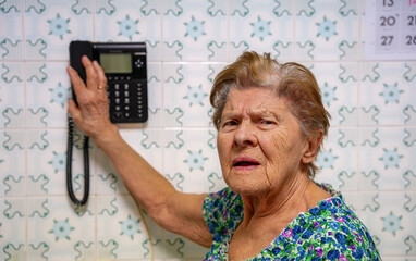 hispanic mature adult woman receiving a call in retro kitchen. Surprise elderly woman receiving telephone call in a vintage kitchen