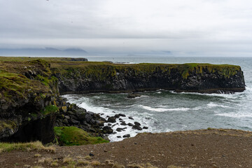 Fototapeta na wymiar Waves washing against black basalt cliffs at Arnarstapi Cliffs in Snaefellsnes Peninsula, Iceland