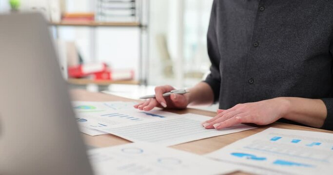 Business woman analyzing project statistics and delivering work report with graphic documents and laptop in office. Strategic planning and financial data analysis concept closeup