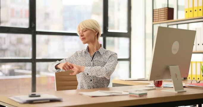 Warmup for laptop at the workplace in office. Woman at laptop pulls herself up and kneads body concept of sedentary work