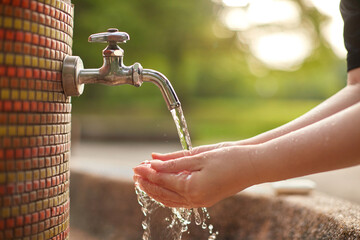 庭の水道水の蛇口で手洗いしている女性の両手の様子 - obrazy, fototapety, plakaty