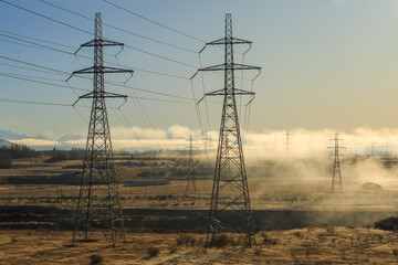 Rows of high-voltage power pylons on a misty winter morning. Photographed near the Ohau B power plant at Twizel, New Zealand