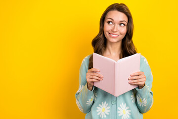 Photo of young cheerful positive smiling hold copybook enjoy reading literature look empty space plans for future isolated on yellow color background