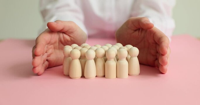 Hands of defender of wooden pawn figurines. Protection safety and insurance of people