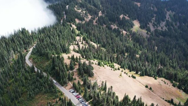Mesmerizing aerial view of mist-covered mountains in Olympic National Park. Parked cars line the road, beckoning adventure in nature's sanctuary.