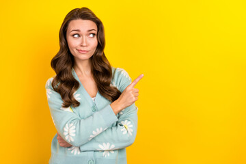 Photo of dreamy unsure lady dressed teal cardigan showing finger looking emtpy space isolated yellow color background